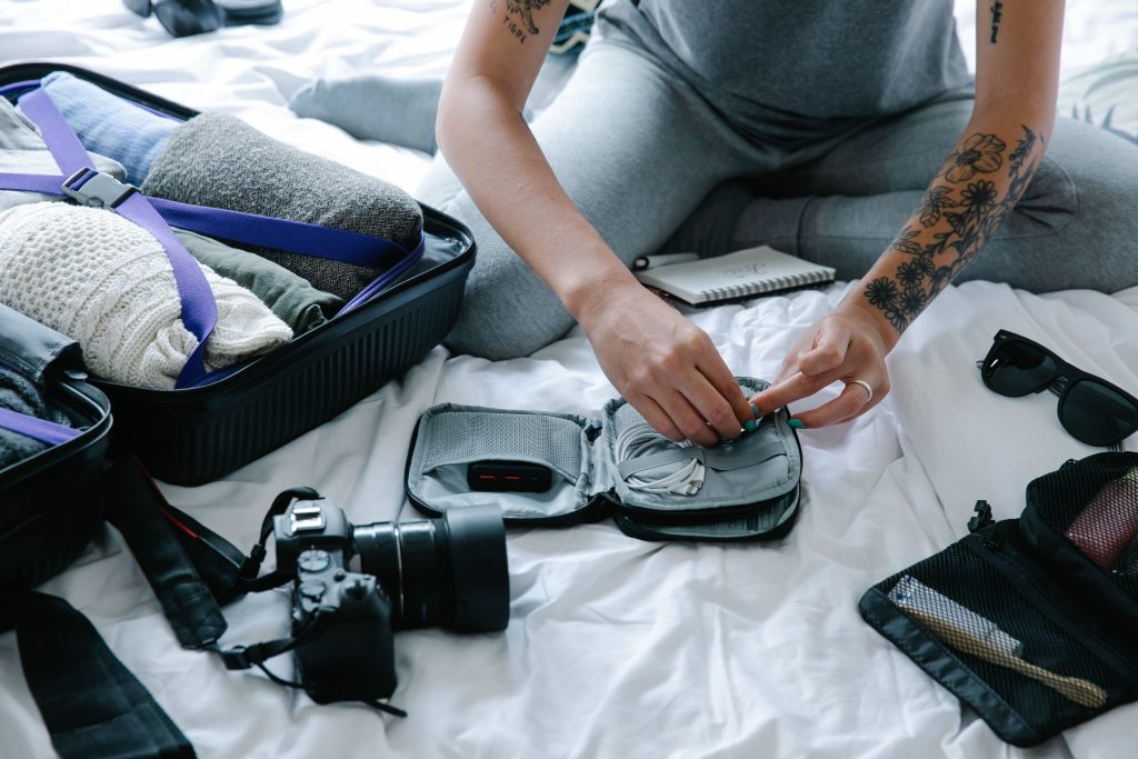 Traveler organizing camera gear, electronics, and clothing while packing a soft-sided duffel bag for a safari